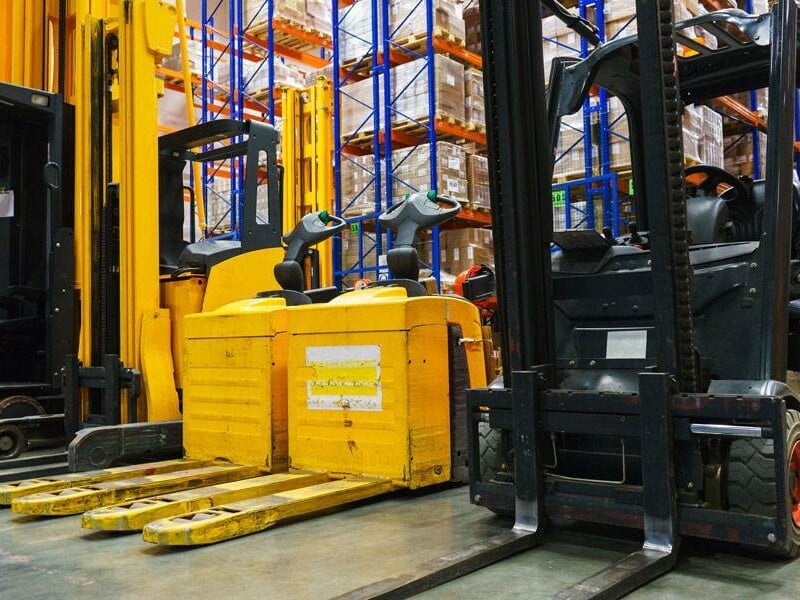 A Pristine Warehouse With Forklifts And Pallet Trucks, Showcasing Organised Storage—Ideal For Efficient Grease Nipple Distribution.