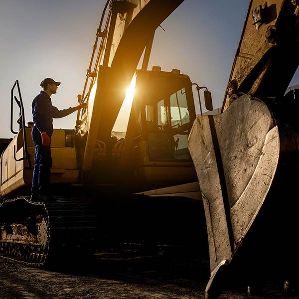 An Industrial Worker Inspects Premium Grease Nipples On An Excavator At Sunset, Highlighting Essential Machine Lubrication Points.